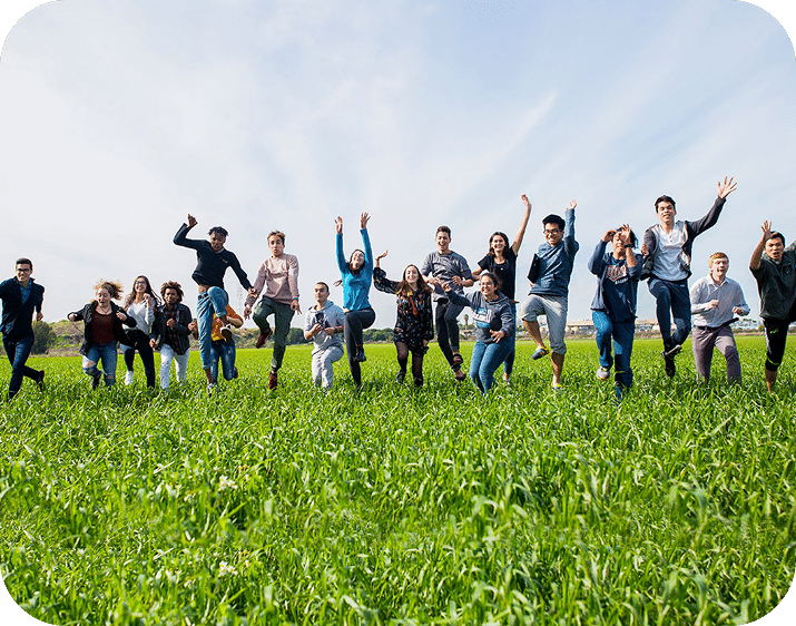 Étudiants de l'EMIS de plus de 40 pays sautant de joie dans un champ vert.